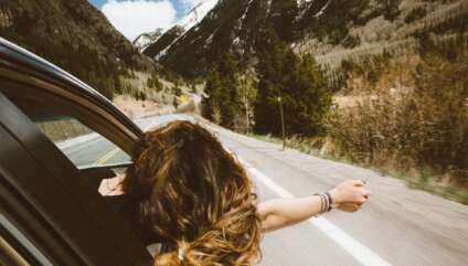 Une femme cheveux au vent à la fenêtre d'une voiture en marche